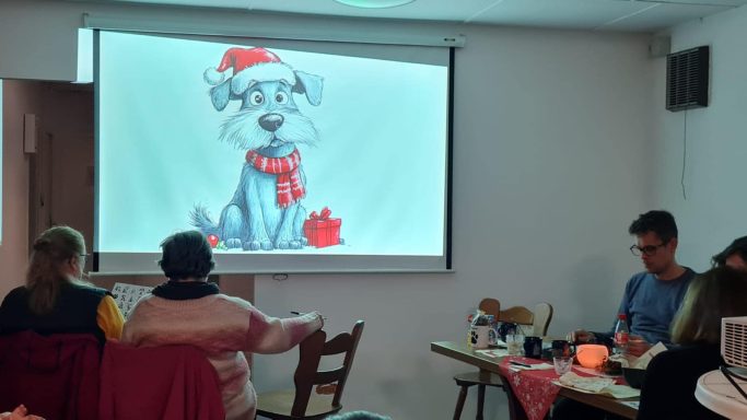 Ein Cartoon-Hund mit Weihnachtsmann-Mütze und Schal, auf einer Leinwand projiziert.