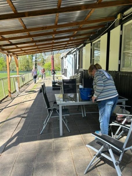 Frau, die an einem Tisch unter einem überdachten Bereich arbeitet, mit Stühlen und einer Aussicht ins Grüne.