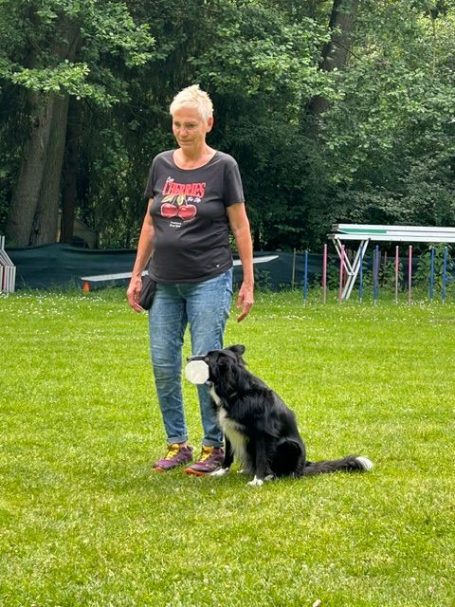 Hundeführerin mit Hund mit Apportel im Maul