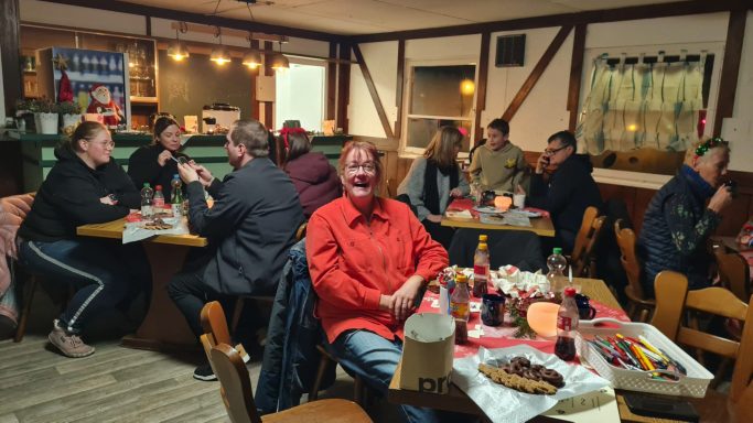 Menschen sitzen in einem festlich geschmückten Gasthaus und genießen die Gesellschaft.