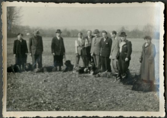 Gruppe von Männern und Frauen steht auf einem Feld in historischen Kleidern.
