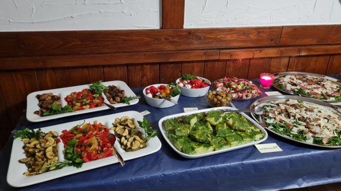 Vielfältige kalte Platten mit Salaten, Gemüse und frischen Beilagen auf einem Tisch.