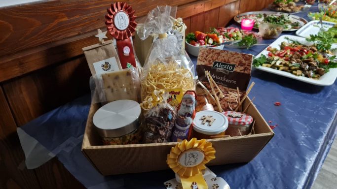 Geschenkkorb mit Snacks, Süßigkeiten und verschiedenen lokalen Produkten.